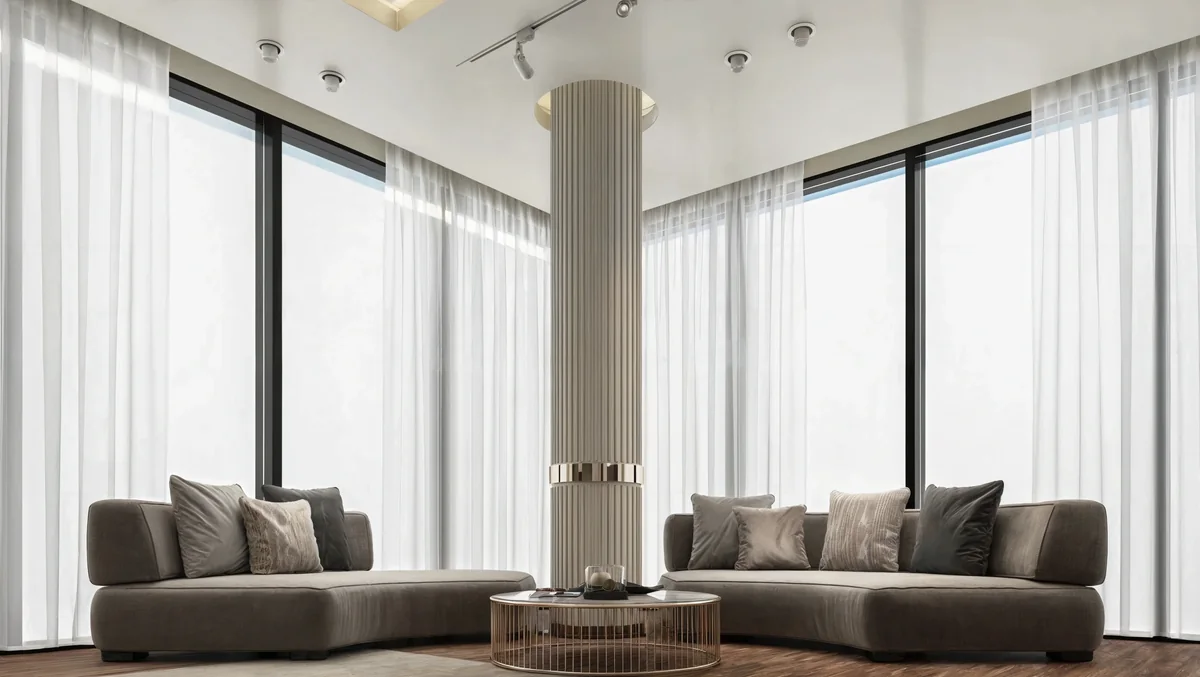 Paired curved sofas around a fluted column and floor-to-ceiling corner windows
