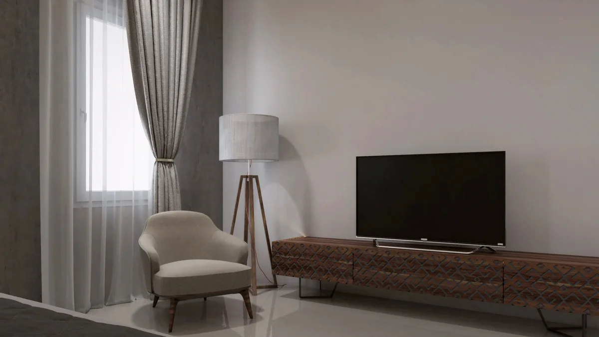 Patterned timber media cabinet and a window-side reading chair in a Dahlan Villa bedroom